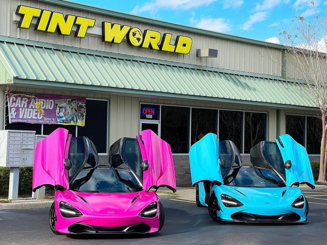 A pink and blue McLaren parked in front of a Tint World franchise